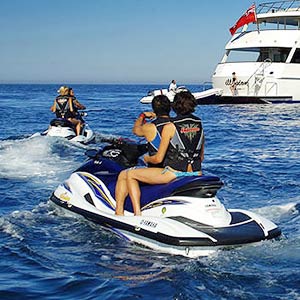 Couples returning to luxury yacht on Jet Skis